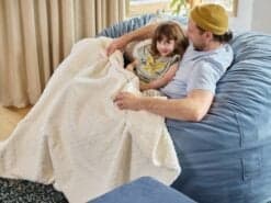 Father and daughter enjoying time on a foam filled Grande bean bag with Polar Calming Blanket in the living room.