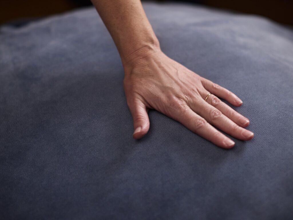 Hand pressing on a Persian Blue foam filled bean bag.