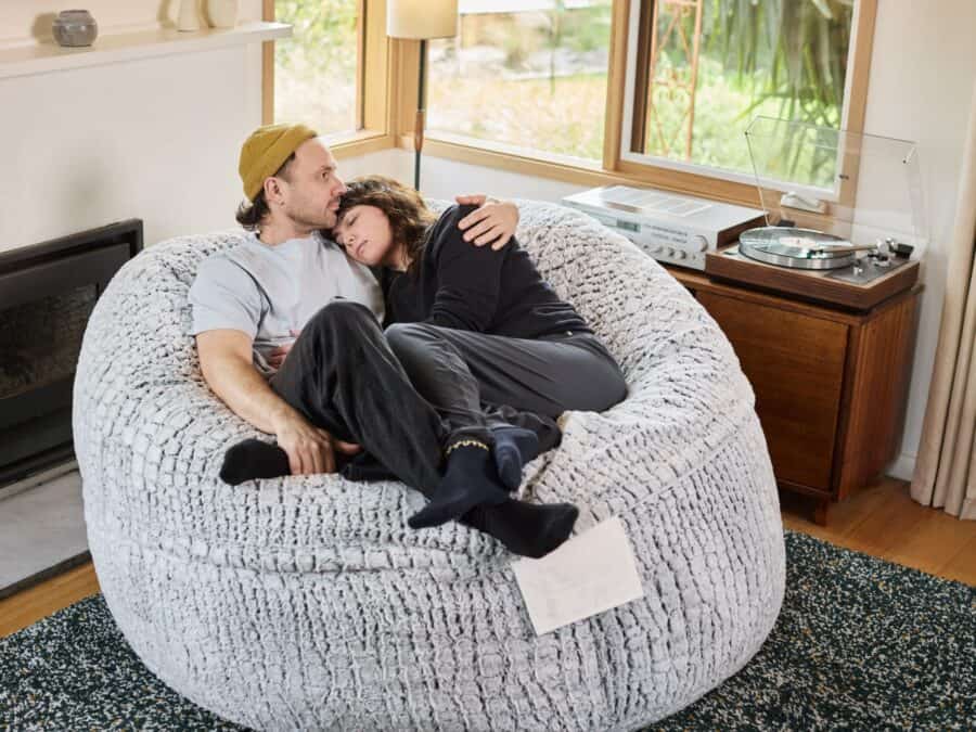 Close-up of a couple relaxing on a foam filled Grande bean bag in a cosy living room.
