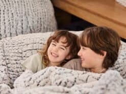 Two children happily relaxing on a foam filled Stone Fur bean bag in a cosy living room.