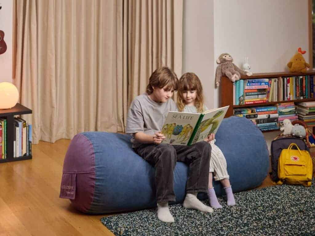 Kids sitting on a blue foam filled SuperSub bean bag reading a book.