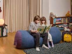 Kids sitting on a blue foam filled SuperSub bean bag reading a book.