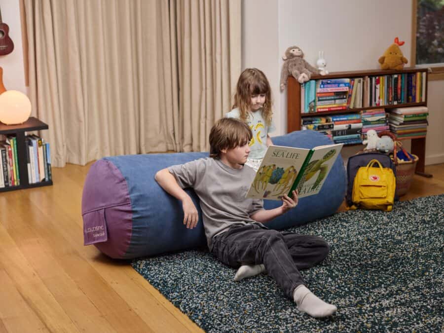 Children relaxing on a foam filled SuperSub bean bag while reading a book together.