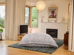 Faux Stone Fur foam filled 3-in-1 bean bag placed on a rug in a calm living room with large windows and modern decor.